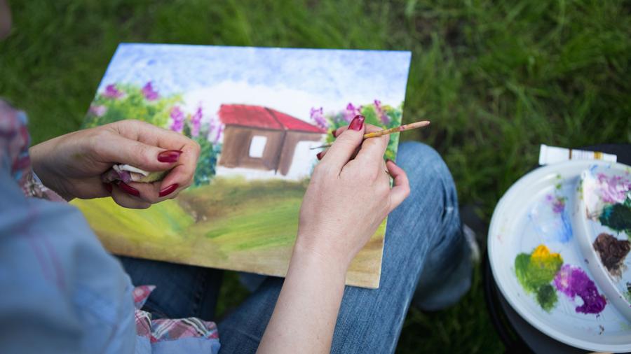 Painting outside on the grass, paints beside her